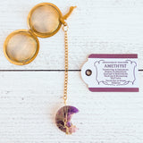 Gold color tea ball infuser for loose leaf tea with moon shaped purple amethyst gemstone crystal wire wrapped with gold wire into tree of life design - includes tag with association and properties of the stone